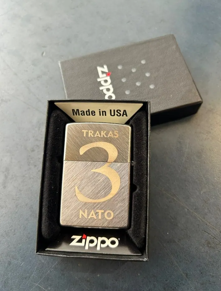 Encendedor metálico con un número grabado, en su caja