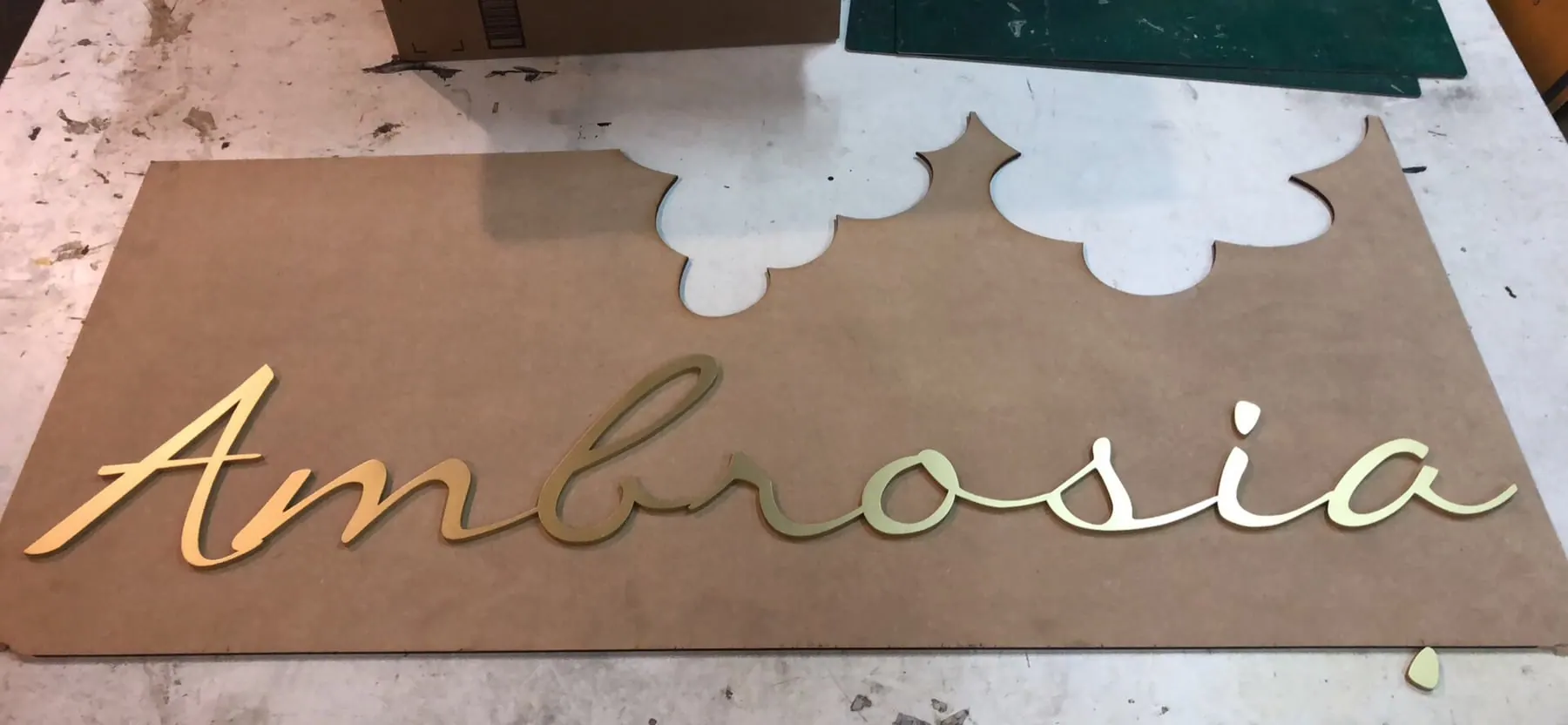 Nombre en letra cursiva dorada recién cortado, sobre la placa de la que salió